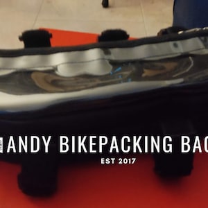 Könnte beinhalten: Schwarze Bikepacking-Tasche mit durchsichtiger Oberseite und einem Logo mit der Aufschrift "ANDY BIKEPACKING BAGS EST 2017".