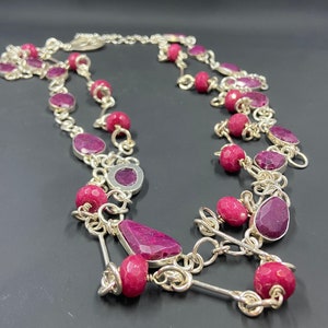 May include: A silver chain necklace with pink gemstone beads. The necklace has a layered design with multiple strands of chain and beads.