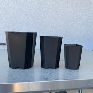 May include: Three black plastic plant pots of different sizes. The pots are square and have a textured surface.