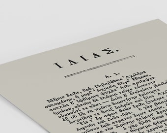 May include: A printed page with Greek text, titled "ΙΛΙΑΣ" (Iliad), in black font on a light gray background. The text is arranged in columns, with numbers on the right side. The paper is slightly angled.