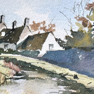 May include: Watercolor painting of a rural landscape featuring several white cottages with dark brown roofs. The scene includes trees with autumn foliage, a grassy area, and a pathway, all rendered in soft blues, greens, and browns.