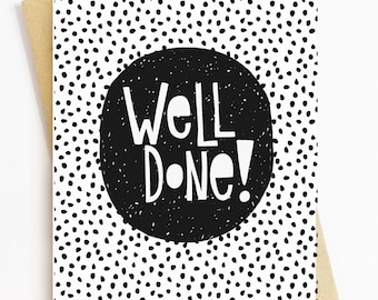 May include: A black and white greeting card with a black circle in the center. The circle has the text "Well Done!" in white. The background is white with black polka dots.