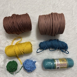 May include: A collection of craft cord in various colors and sizes, including two large brown spools, one yellow spool, one dark blue bundle, one small green ball, one small light blue ball, and one teal spool labeled Bonnie 4 mm 50 yd/45 m.
