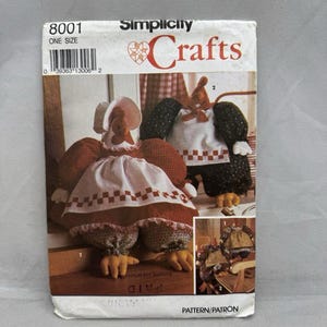 May include: A Simplicity Crafts sewing pattern envelope, number 8001, featuring illustrations of two fabric chicken dolls. The front shows a chicken in a red dress and white bonnet, and another in a black outfit. Text includes '8001', 'ONE SIZE', and 'Crafts'.