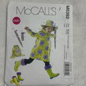 May include: A McCall's M6392 sewing pattern envelope for children's sizes 3-4, 5-6, and 7-8. The front features illustrations of a raincoat, hat, boots, umbrella, and drawstring bag, all decorated with a yellow and purple floral pattern.