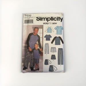 以下が含まれることがあります： Simplicity 9499 easy to sew パターン封筒。ラグランスリーブのシャツ、パンツ、ショートパンツのイラストが描かれています。チェック柄や無地の生地のバリエーションがあり、表紙には青と黒のお揃いの服を着た二人の写真が掲載されています。
