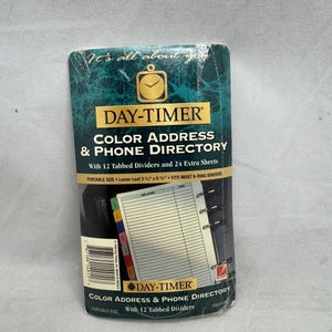 May include: A Day-Timer color address and phone directory in a portable size of 3.75 inches by 6.75 inches. The packaging features a teal marble background, a clock icon, and includes 12 tabbed dividers and 24 extra loose-leaf sheets for 6-ring binders.