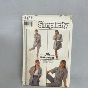 May include: A Simplicity Jiffy Wardrobe sewing pattern envelope, number 8479, featuring illustrations of various outfits including a striped blazer, shorts, and pants. The white paper envelope displays the brand name and text 5 easy pieces.