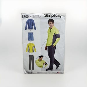 May include: Simplicity sewing pattern 8705 for a quarter-zip pullover and trousers. The envelope displays illustrations of a blue patterned pullover, blue shorts, a yellow and grey pullover, and grey trousers, alongside a photo of a person wearing the yellow pullover.