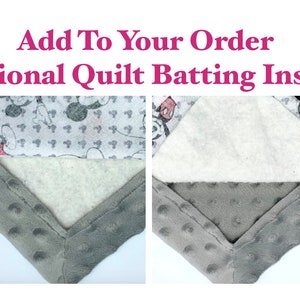 May include: Close-up of two corners of a quilt showing the layers of fabric. The top layer is a white fabric with a black and red Mickey Mouse print. The middle layer is a white batting. The bottom layer is a gray minky fabric with a textured pattern.