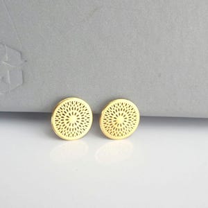 May include: A pair of gold-toned earrings with a circular design featuring a delicate, intricate pattern.