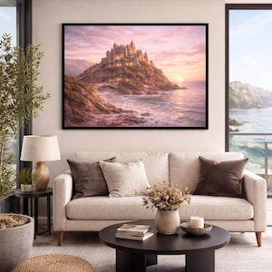May include: A framed print of a castle on a mountain overlooking the ocean at sunset. The castle is lit with warm lights. The print is displayed above a beige sofa with brown and beige pillows. A round black coffee table and a woven ottoman are in front of the sofa.