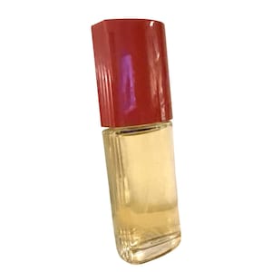 May include: A small, rectangular perfume bottle with a red cap. The bottle is filled with a light yellow liquid. The cap is a solid, glossy red, and the bottle is clear glass.