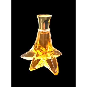 May include: A clear, star-shaped perfume bottle with a gold-colored cap. The bottle is filled with a golden-colored liquid. The design features a unique, floral-inspired shape, adding a touch of elegance. The background is black.