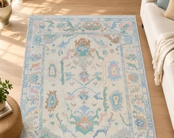 May include: A rectangular area rug featuring a cream-colored base with a symmetrical floral and vine pattern in soft pastel shades of light blue, sage green, dusty pink, and muted orange, framed by a decorative border with repeating motifs.