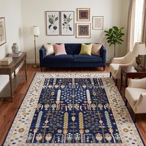 May include: A large rectangular area rug featuring a deep navy blue central field adorned with a symmetrical botanical pattern of stylised trees and floral motifs in shades of cream, sage green, soft pink, and gold, framed by a wide cream border.