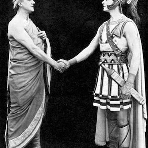 May include: A black and white photo of two men shaking hands. The man on the left is wearing a toga and the man on the right is wearing a Roman soldier's uniform with a helmet and a sword.