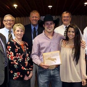 Op de afbeelding: Een groep mensen staat samen en glimlacht. Een man met een cowboyhoed houdt een certificaat vast met de tekst "President's List Fall 2012".