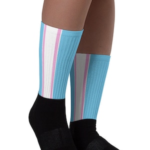 Puede incluir: Un par de calcetines a rayas azules y rosas con puños negros en los tobillos. Los calcetines están hechos de un material suave y cómodo y son perfectos para el uso diario.