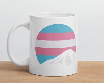 May include: White ceramic mug with a graphic of Mount Fuji in front of a transgender pride flag.