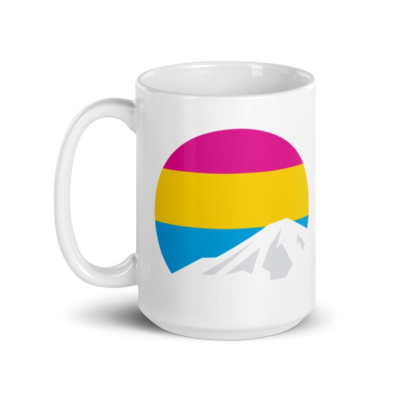 May include: White ceramic mug with a graphic of a mountain silhouette in front of a circle with horizontal stripes of pink, yellow, and blue.