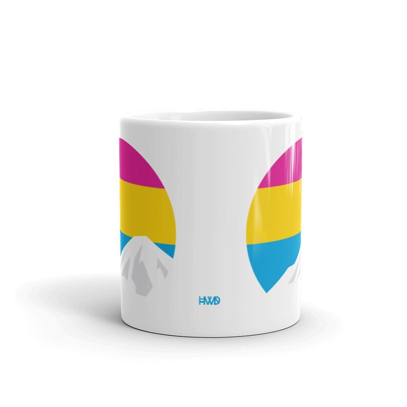 May include: White ceramic mug with a pansexual pride flag design. The flag is in the shape of a mountain with a pink, yellow, and blue color scheme. The mug has the text "HWD" on the bottom.