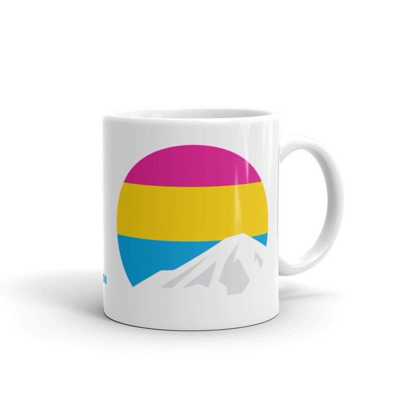 May include: White ceramic mug with a graphic of a mountain and a circle with horizontal stripes of pink, yellow, and blue.