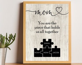 May include: A framed print with a woodgrain background and the text "mom" with a heart. The text "You are the piece that holds us all together" is below the word "mom".  Four puzzle pieces are below the text, with the names "Noah", "Mom", "Emma", and "Jacob" written on them.