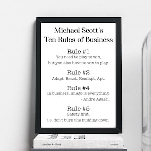 Puede incluir: Una impresión enmarcada en negro con texto blanco que dice "Michael Scott's Ten Rules of Business" con cinco reglas enumeradas. La impresión está en un estante de madera con una cúpula de vidrio que contiene una pequeña planta y una pila de libros.