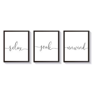 May include: Three black framed prints with white backgrounds and black calligraphy. The prints read "relax", "soak", and "unwind".