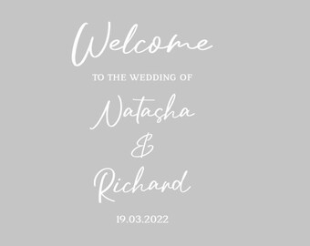 May include: A light gray wedding welcome sign with white cursive text. The sign reads "Welcome to the wedding of Natasha & Richard 19.03.2022". The sign is simple and elegant.