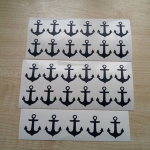 May include: Sheets of white stickers featuring black anchor designs. The stickers are arranged in three rows, with multiple anchors per sheet. The anchors are a classic nautical symbol.