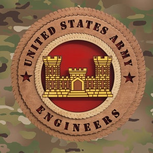 May include: A round wooden sign with the words "United States Army Engineers" in a brown rope-like border. The centre of the sign features a red background with a gold castle-like structure.