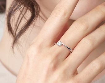 May include: A simple silver band ring with a single small round diamond in the center.