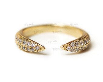 May include: A gold ring with two pointed ends, both set with small clear stones.
