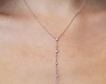May include: A delicate silver chain necklace with five small, clear gemstones hanging in a vertical line.