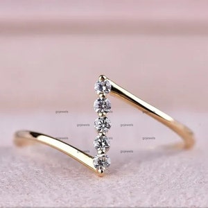 May include: A delicate gold ring with a chevron design featuring five small round diamonds.