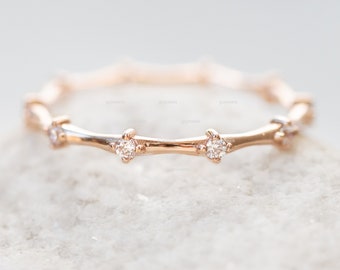May include: A delicate rose gold band ring with a minimalist design featuring small diamonds set in a twig-like pattern.