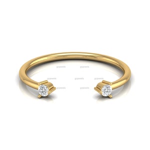 Peut inclure: Une bague en or avec deux petits diamants ronds sertis dans la bande. La bague est simple et élégante.