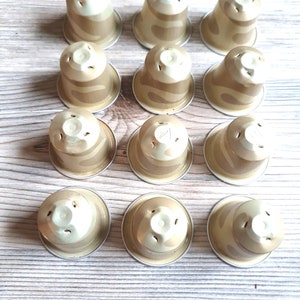 May include: Twelve beige and white coffee pods with a swirl pattern. The pods are arranged in three rows of four.