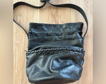 May include: Black leather bucket bag with a braided detail and a long adjustable strap.