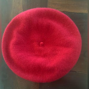 May include: A solid red beret made of felt.