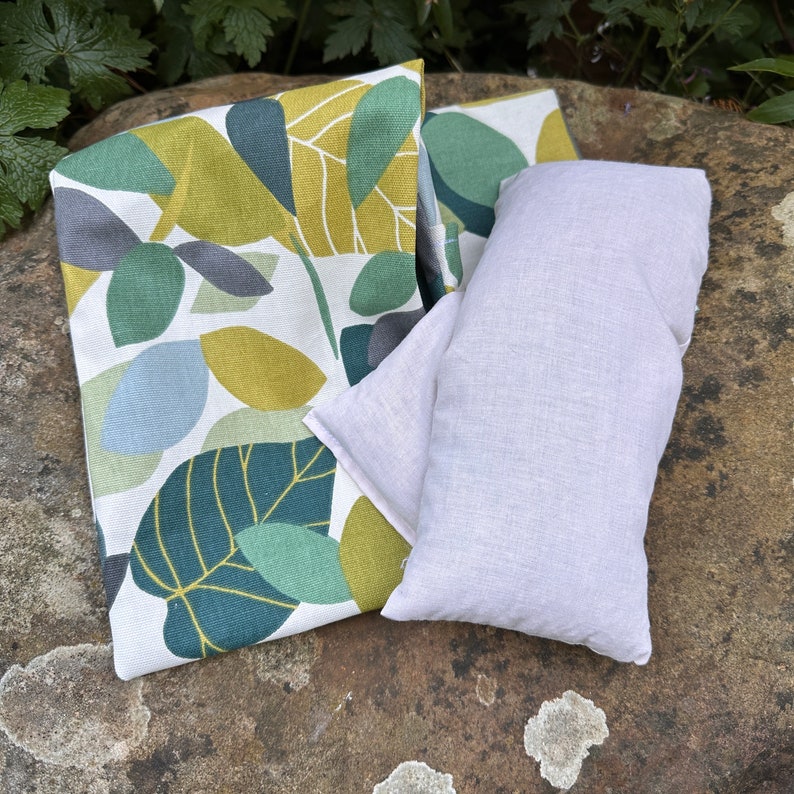 Green spruce botanical printed reusable heat pad with removable cover. Plain microwave wheat bag with fragrant dried lavender and washable cover with envelope opening for ease of removal for washing, heating and cooling.
