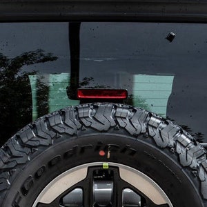 May include: A white vinyl sticker on the back window of a silver car. The sticker says "mud inside" in a white oval with a black outline.