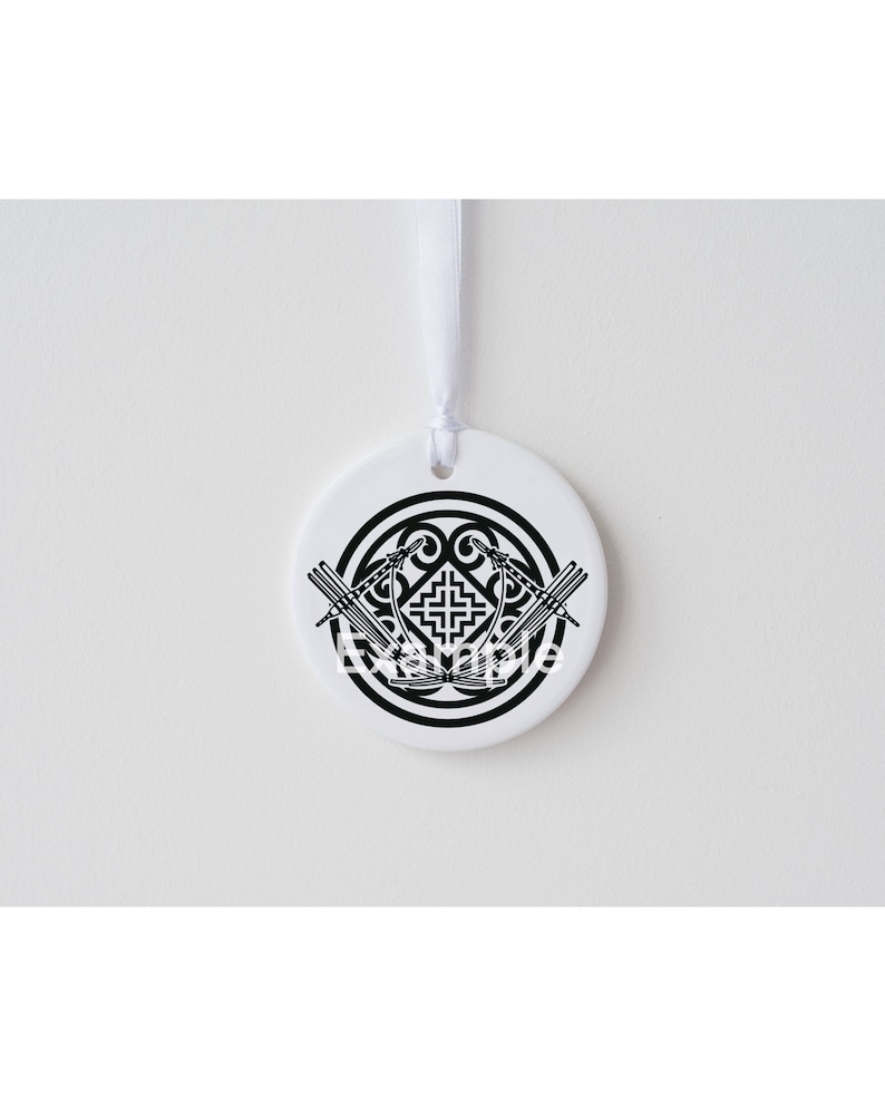 May include: White ceramic ornament with a black Celtic knot design. The knot is surrounded by a circle and has two stylized swords crossing in the center.