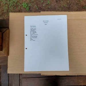 Puede incluir: Una hoja de papel blanca con una lista de nombres y títulos, incluyendo "Fox Mulder", "Dana Scully", "Lauren Kyse", "Jane Morris", "Teenager", "Patólogo", "Yo", "Saunges", "Ms. Winn", "Robert Dorland", "Policía", "Jardinero", "Ellen Bledsoe", "Dr. Phillips", "Hombre", "Mujer" y "Ms. Lange". El texto "The X-Files" está en la parte superior de la página, junto con "Shadows" y "Cast". La fecha "8/13/93" está en la esquina superior derecha.
