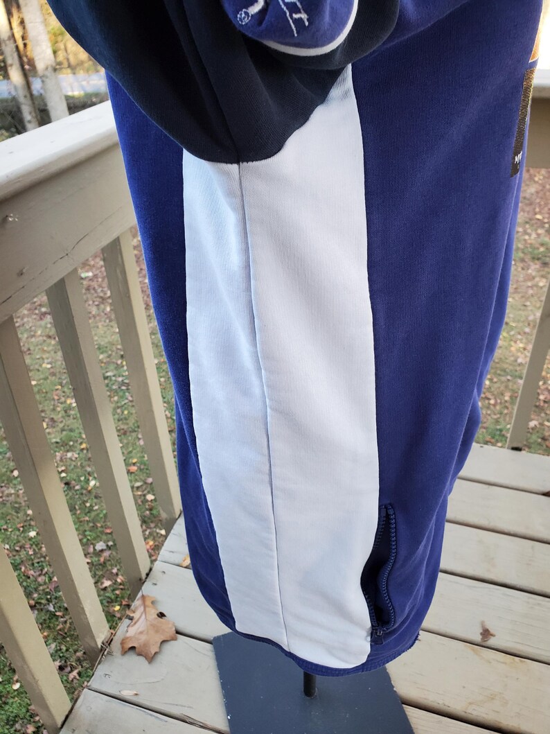 May include: A blue and white hooded sweatshirt with a white vertical stripe down the side. The sweatshirt has a black hood and a zippered pocket. The garment is displayed on a mannequin.