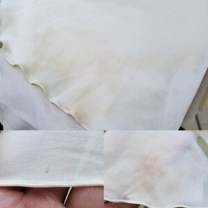 Puede incluir: Primer plano de una tela blanca con una superficie ligeramente texturizada. Hay algunas manchas marrones tenues en la tela.