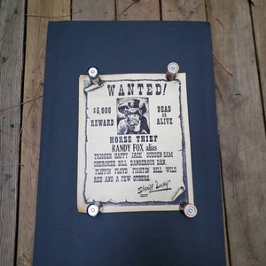 Puede incluir: Un cartel de se busca vintage con un dibujo de un hombre con bigote y sombrero de vaquero. El cartel dice "WANTED!" y "HORSE THIEF RANDY FOX alias" con una recompensa de $ 5,000. El cartel también enumera otros alias para el hombre buscado.