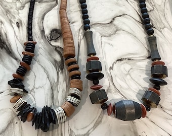 May include: Two wooden bead necklaces, one with black and brown beads, the other with black, brown, and white beads.